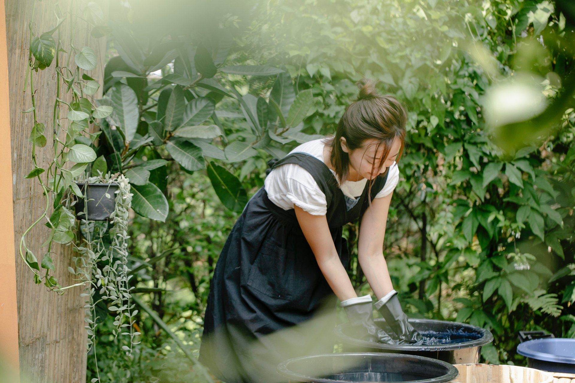 Woman washing jeans in a big bucket