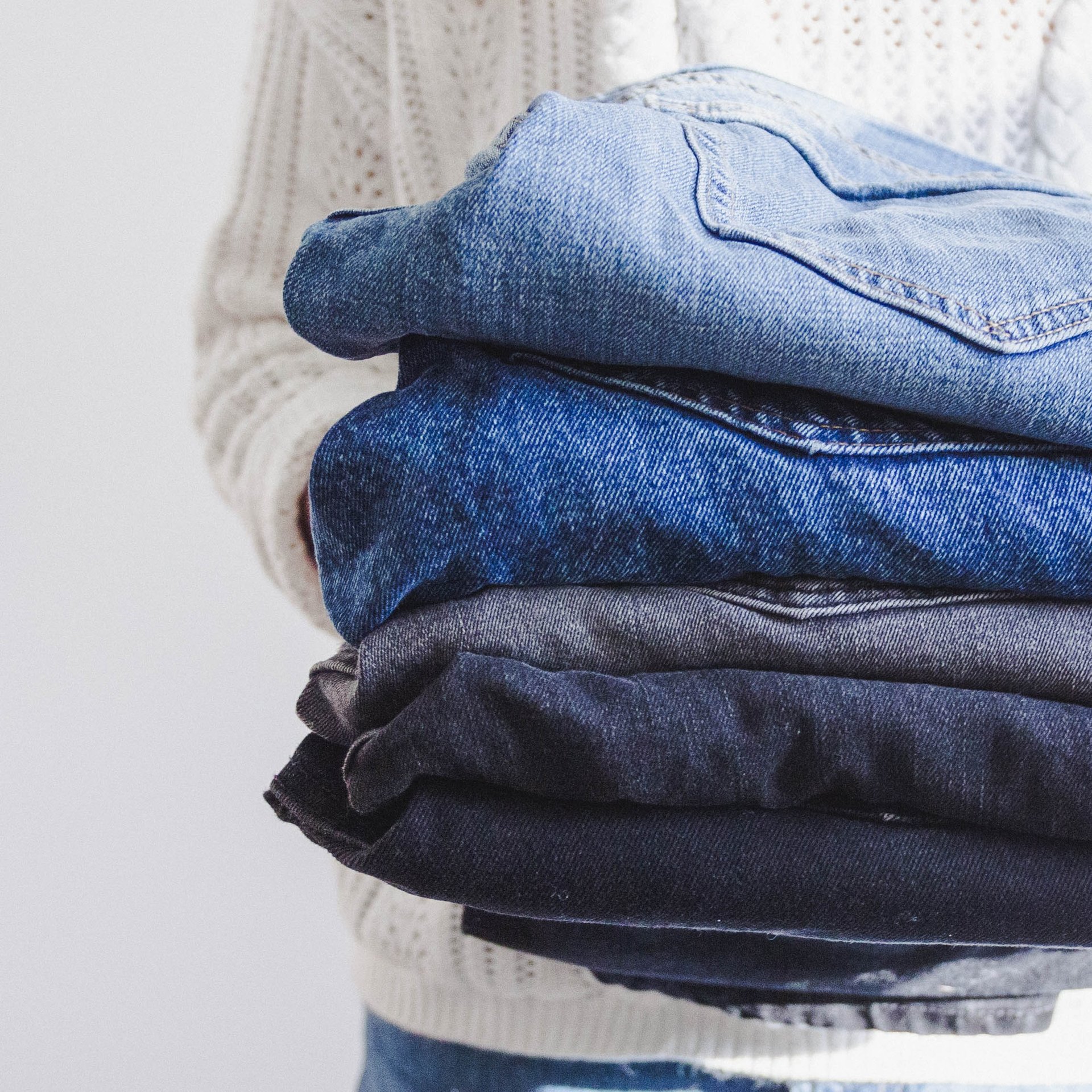 Woman holding stack of jeans