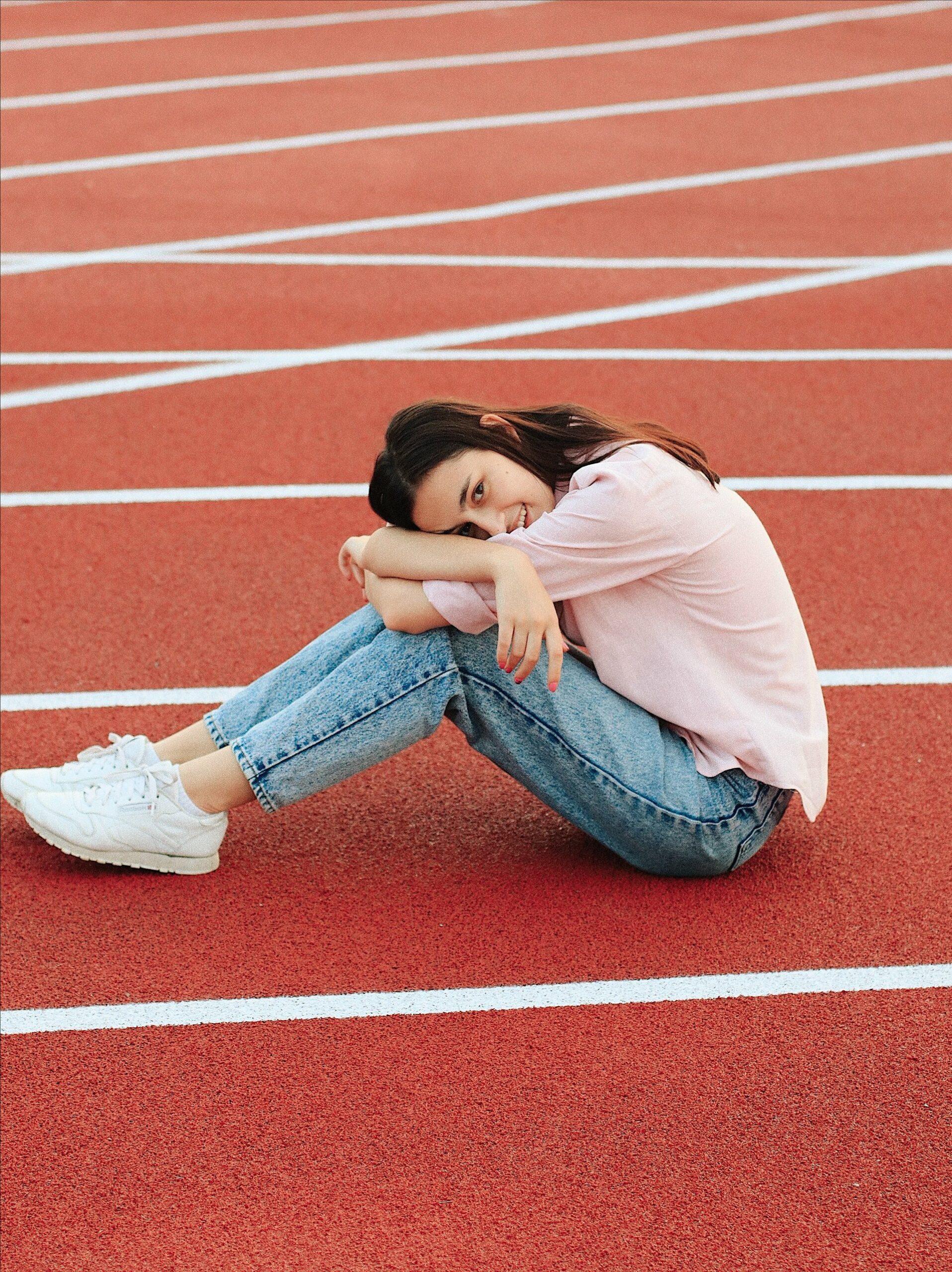 How to wear running shoes with jeans - woman wearing pink shirt and jeans with white sneakers